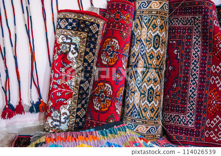 stack of rolled up traditional oriental uzbek handmade carpets at the market in Uzbekistan 114026539