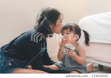 Asian older sister kissing younger sister on the forehead. Sibling relationship 114026805