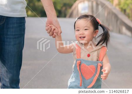Asian father walking with daughter in park, Parents hold the baby's hands, Happy family in the park evening light. Happy family concept 114026817