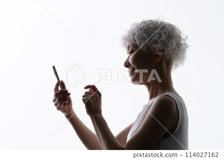 Senior woman operating a smartphone silhouette Senior woman operating a smartphone silhouette 114027162