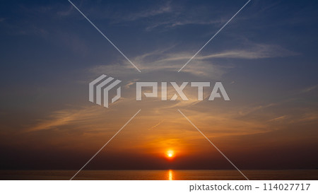 The setting sun and flowing clouds in the evening sky The setting sun and flowing clouds in the evening sky 114027717