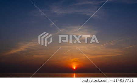 The setting sun and flowing clouds in the evening sky The setting sun and flowing clouds in the evening sky 114027731