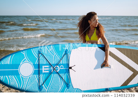Woman surfer walks with a board on the sandy beach. Extreme sport. Travel, weekend, lifestyle. Woman surfer walks with a board on the sandy beach. Extreme sport. Travel, weekend, lifestyle. 114032339