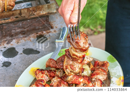 Cooked kebabs on the grill with smoke. Fresh brown BBQ meat cooked on an outdoor grill 114033864