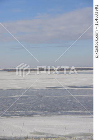 the lake is covered with ice in winter and sunny weather 114033993
