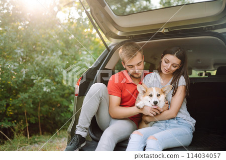 Happy couple is petting their beloved corgi dog. Concept of lifestyle, vacation, travel, family. 114034057