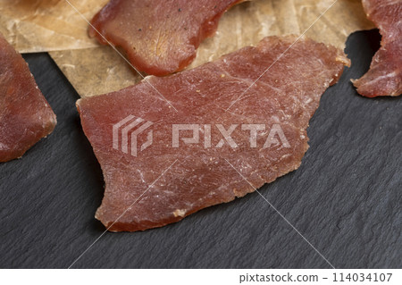 pieces of dried pork with spices and salt on crumpled paper 114034107