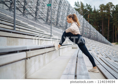 Young woman in sports outfit doing exercises outdoors in morning. Concept of sports, yoga or fitness 114034694