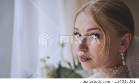 The bride with a bouquet at the window. 114035391