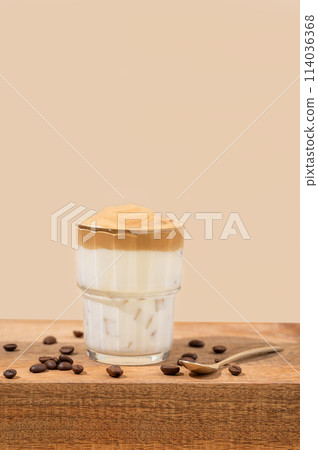 Dalgona coffee. Whipped instant coffee in a glass on a wooden table with coffee beans 114036368