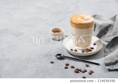 Dalgona coffee. Whipped instant coffee in a glass with coffee beans on a blue background Dalgona coffee. Whipped instant coffee in a glass with coffee beans on a blue background 114036390