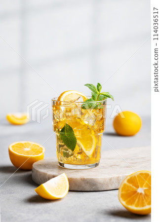Iced drink with lemon, mint in a glass on a marble board on a light background with shadow Iced drink with lemon, mint in a glass on a marble board on a light background with shadow 114036517