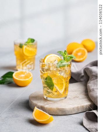Two glasses with iced drink with lemon and mint  on a marble board on a light background with shadow 114036522