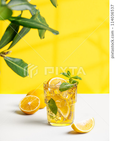 A glass of iced tea with lemon and mint on a yellow and white background with a shadow A glass of iced tea with lemon and mint on a yellow and white background with a shadow 114036537