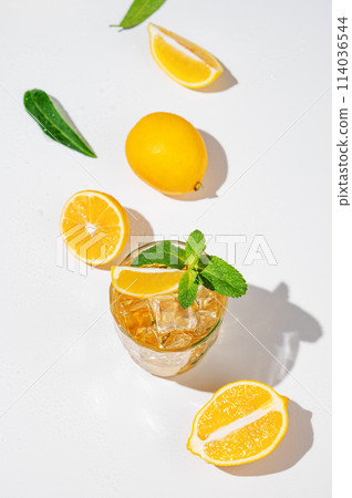 Flat lay of Iced tea with lemon and mint on white background with a shadow and citrus fruits. 114036544
