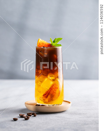 Espresso coffee with orange juice (bumble) in a tall glass with ice and mint on a blue background 114036592