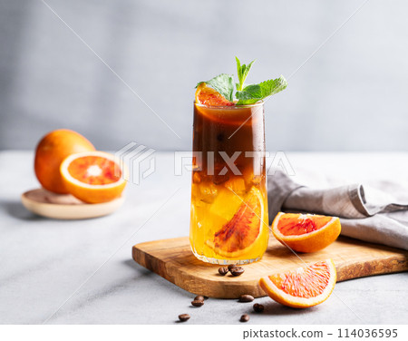 Coffee with orange juice (bumble) in a tall glass with ice and mint on a wooden board Coffee with orange juice (bumble) in a tall glass with ice and mint on a wooden board 114036595