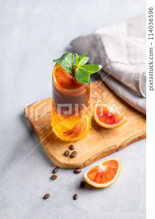 Coffee with orange juice (bumble) in a tall glass with ice and mint on a wooden board  114036596