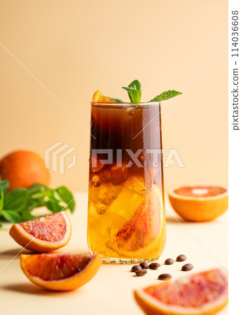 Americano coffee with orange juice (bumble) in a tall glass with ice and mint on a yellow background 114036608