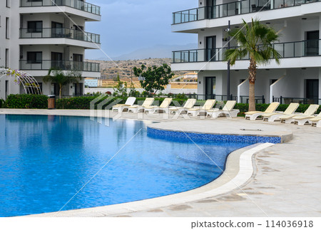 Closeup of towels on lounge chairs near a luxury swimming pool 3 114036918