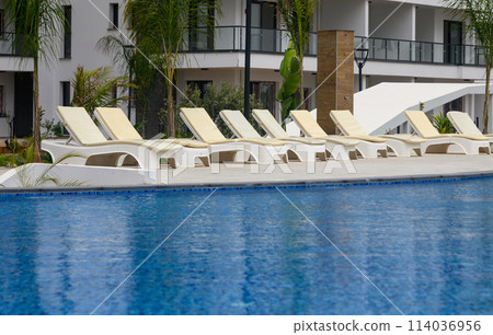 Closeup of towels on lounge chairs near a luxury swimming pool 2 Closeup of towels on lounge chairs near a luxury swimming pool 2 114036956
