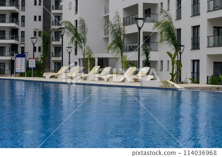 Towels on sunbeds around swimming pool 3 114036968