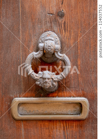 Antique details on an old wooden door. Medieval door handle. 114037552