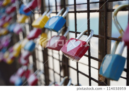 Colorful padlocks in the shape of heart on the fence. 114038959