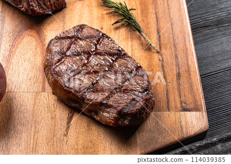 Fresh juicy delicious beef steak on a dark background. Meat dish with spices and herbs 114039385