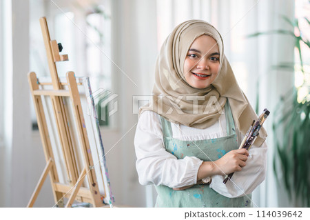 Confident muslim young female artist painting on canvas at home. Hobby and leisure concept. 114039642