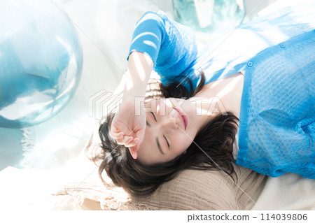 A beautiful woman lying down in the dazzling summer sunshine with her eyes closed. Also used as a beauty image for the beach, summer tanning and UV protection. A beautiful woman lying down in the dazzling summer sunshine with her eyes closed. Also used as a beauty image for the beach, summer tanning and UV protection. 114039806