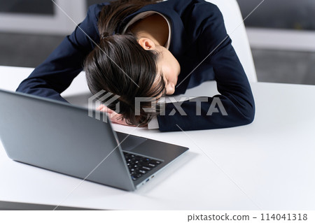 Businesswoman falling asleep during long working hours Businesswoman falling asleep during long working hours 114041318
