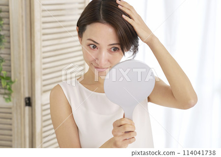 中年婦女對著鏡子檢查自己的頭髮 114041738