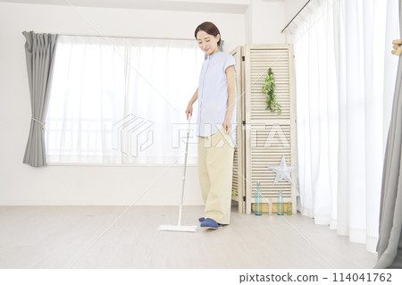 A housewife cleaning the living room with a floor wiper A housewife cleaning the living room with a floor wiper 114041762