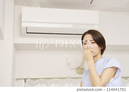 A woman who is bothered by the smell of her air conditioner filter A woman who is bothered by the smell of her air conditioner filter 114041781