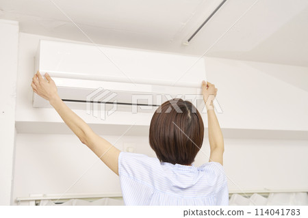 A woman cleaning an air conditioner filter A woman cleaning an air conditioner filter 114041783