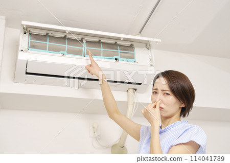 A woman who is bothered by the smell of her air conditioner filter 114041789