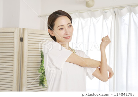 Woman stretching her arms at home Woman stretching her arms at home 114041793