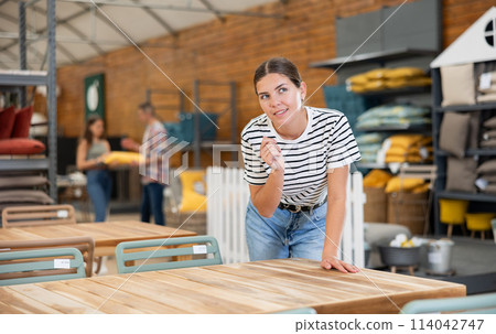 Interested young female shopper looking for outdoor table in store 114042747