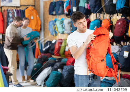Buyer guy chooses summer backpack in store for hikes Buyer guy chooses summer backpack in store for hikes 114042799