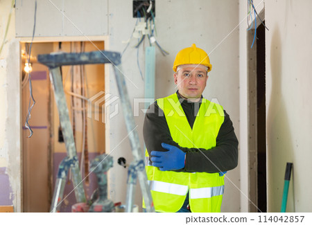 Repair man standing in apartment and looking at camera 114042857