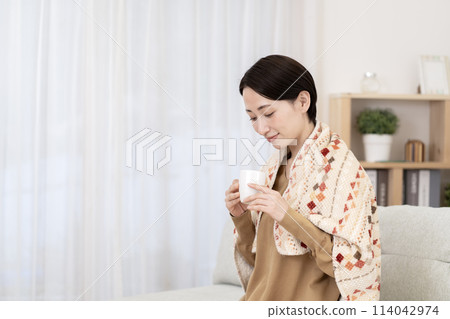 Woman relaxing in the living room, warming up, poor circulation 114042974