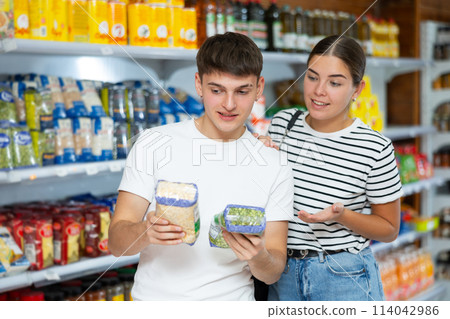 Young married couple carefully checks the information on product labels in hypermarket Young married couple carefully checks the information on product labels in hypermarket 114042986