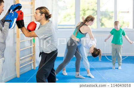 Man works out strength and speed of boxing punch mitts with help of partner in boxing paws Man works out strength and speed of boxing punch mitts with help of partner in boxing paws 114043058