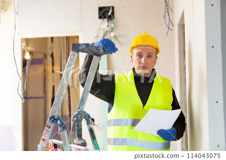 Repair man standing in apartment with documentation Repair man standing in apartment with documentation 114043075