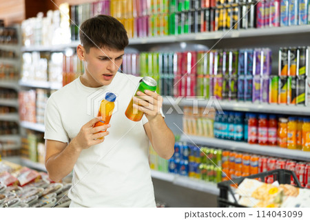 Thoughtful young guy choosing soft drinks in grocery store 114043099