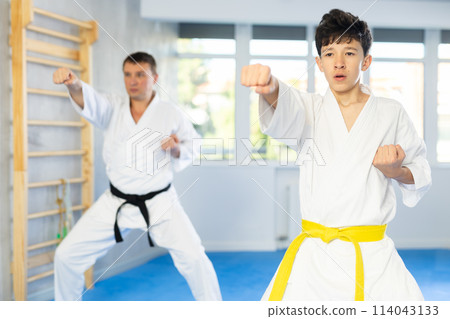 Teen boy wearing kimono training karate techniques during workout session 114043133