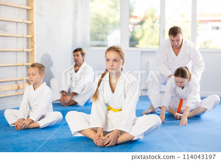 Big family before training karate martial arts performs stretching butterfly Big family before training karate martial arts performs stretching butterfly 114043197