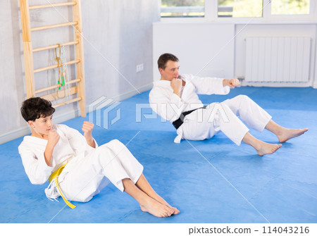 Teenage boy and middle-aged man training fist strikes lying in press position Teenage boy and middle-aged man training fist strikes lying in press position 114043216
