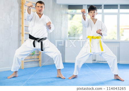 Teen boy and middle-aged man wearing kimono training karate techniques 114043265